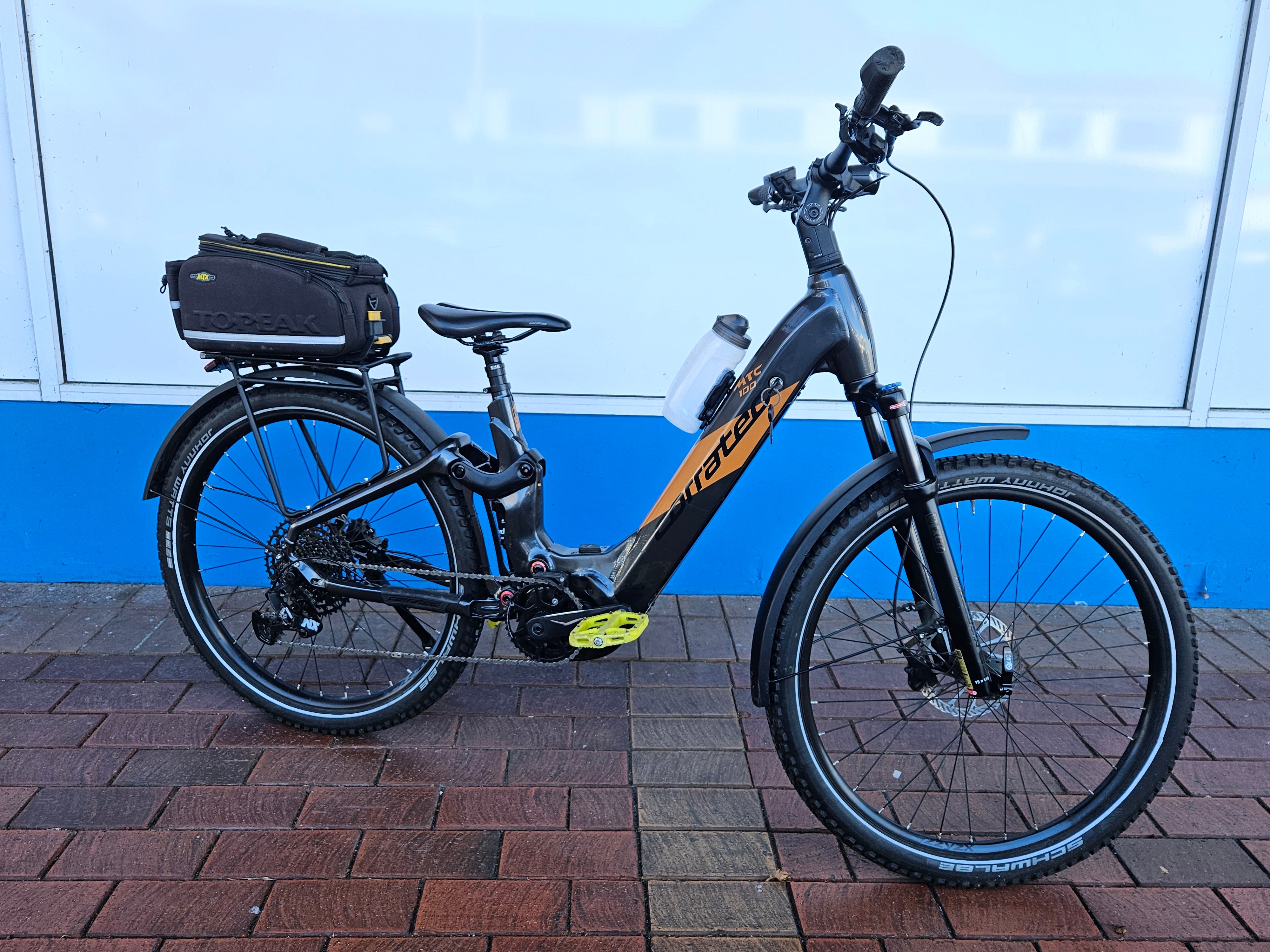 Electric bicycle with a black frame and visible brand logo on a brick pavement.