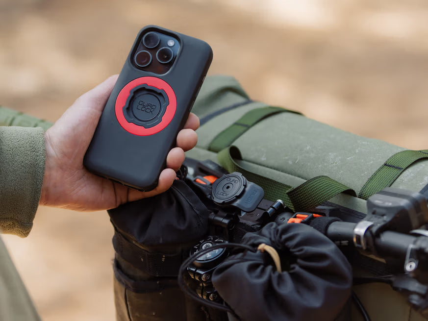 Person holding a phone with a black case featuring Quad Lock phone case, with bike and Quad Lock Stem Cap Mount – Adjustable mounted on the bike