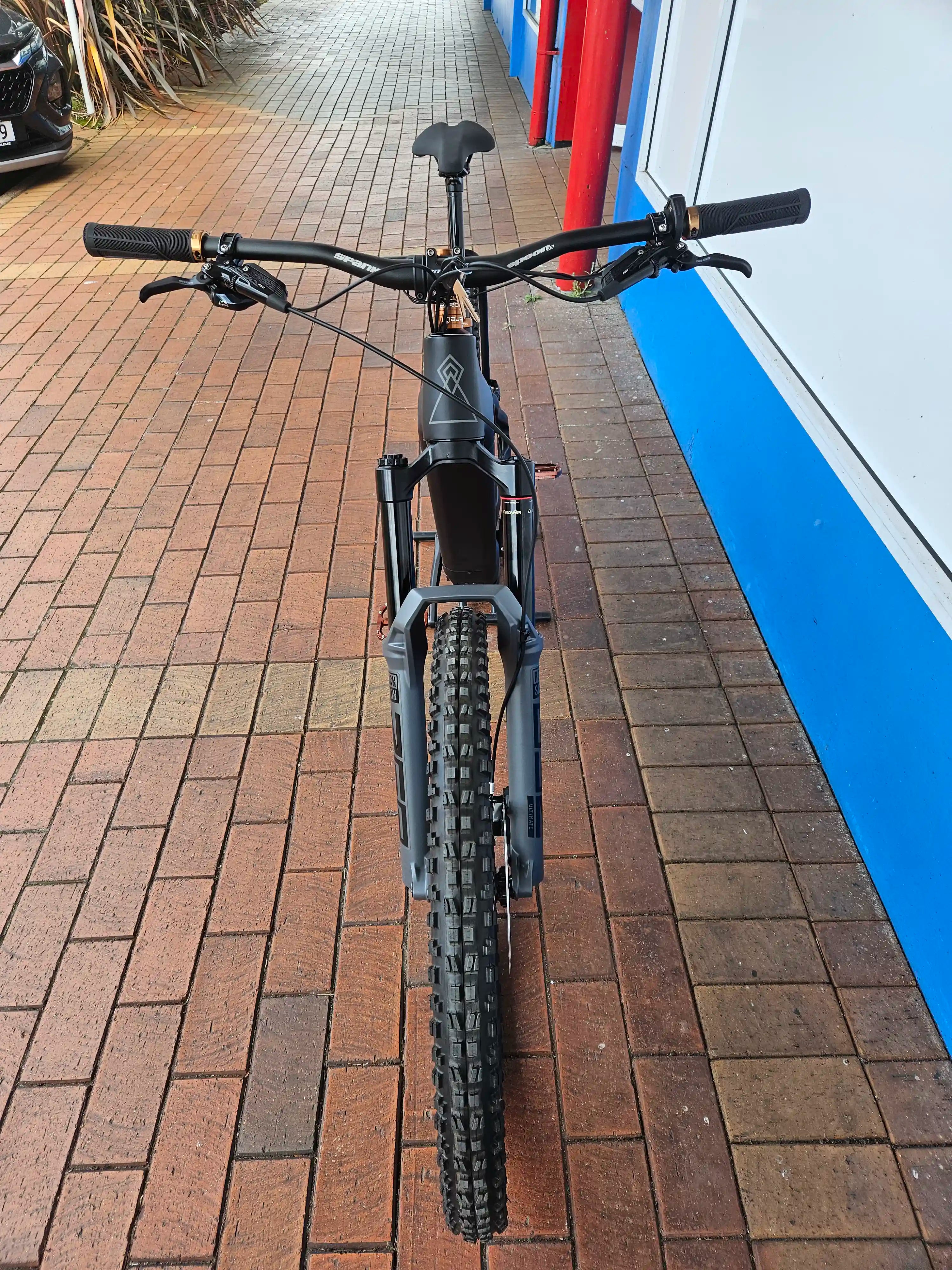 Black Rhyolite Prime E-MTB on a brick pavement with a blue wall in the background