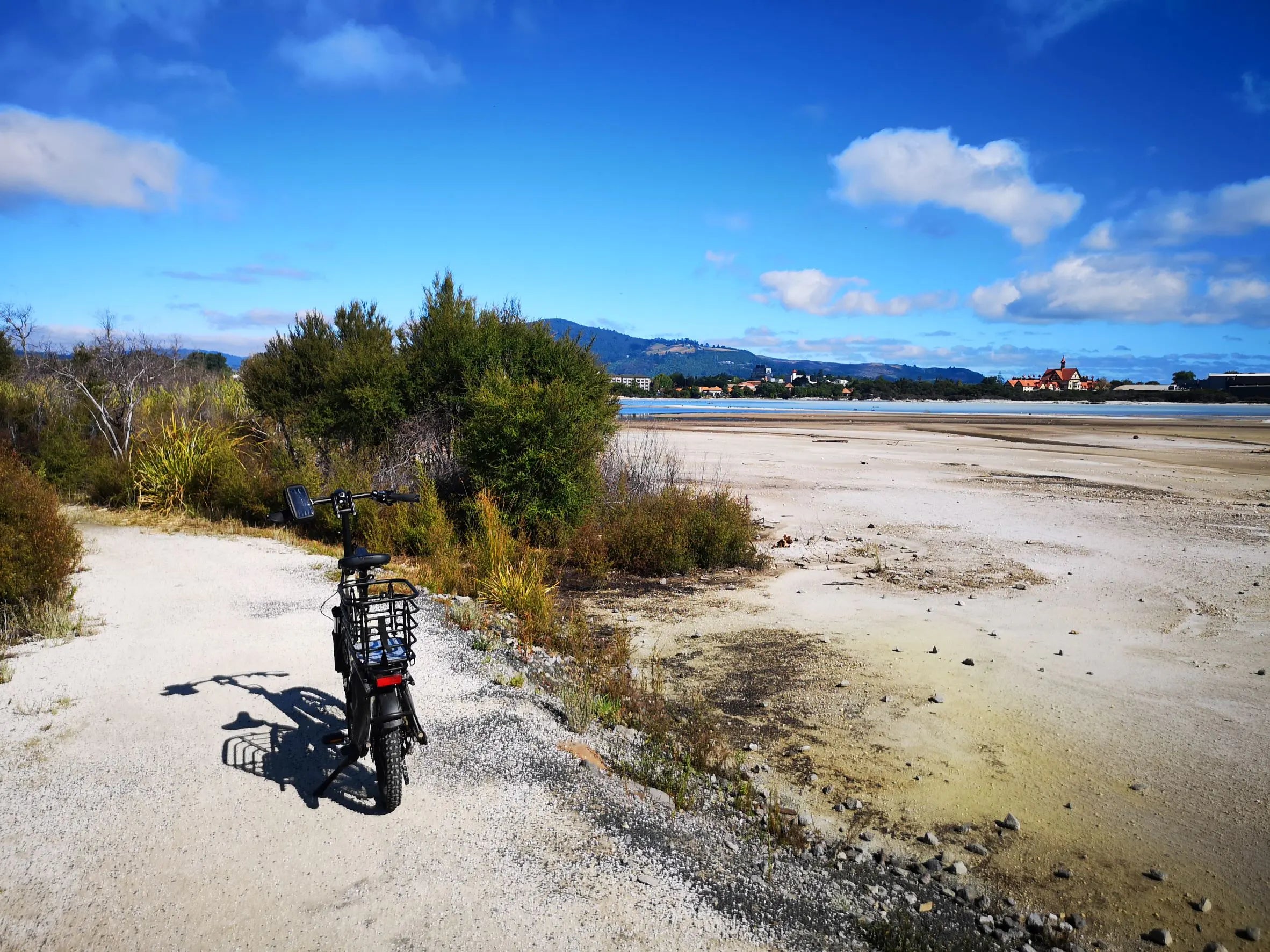 bike parked on a dirt path near rotorua lake with city and mountains in the background