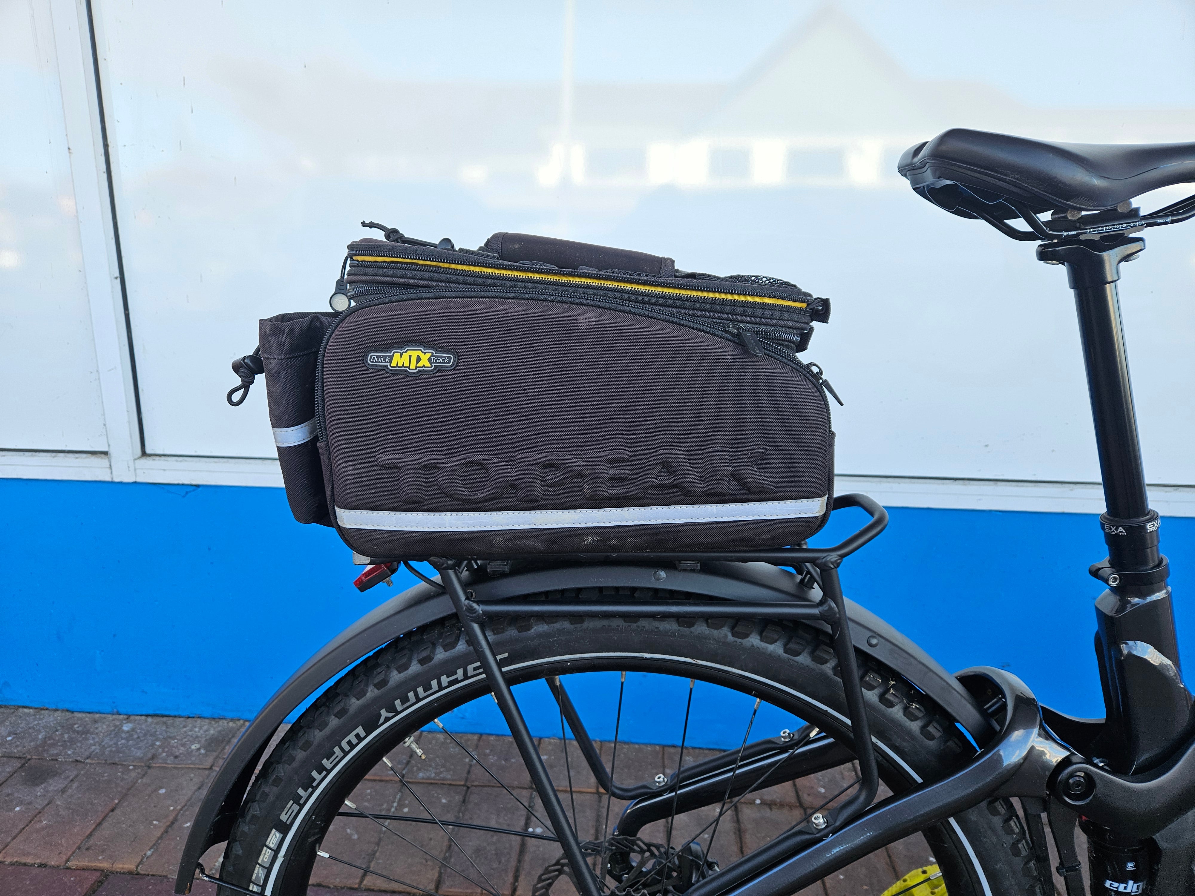 Bicycle with a Topeak bag attached to the back against a blue wall.