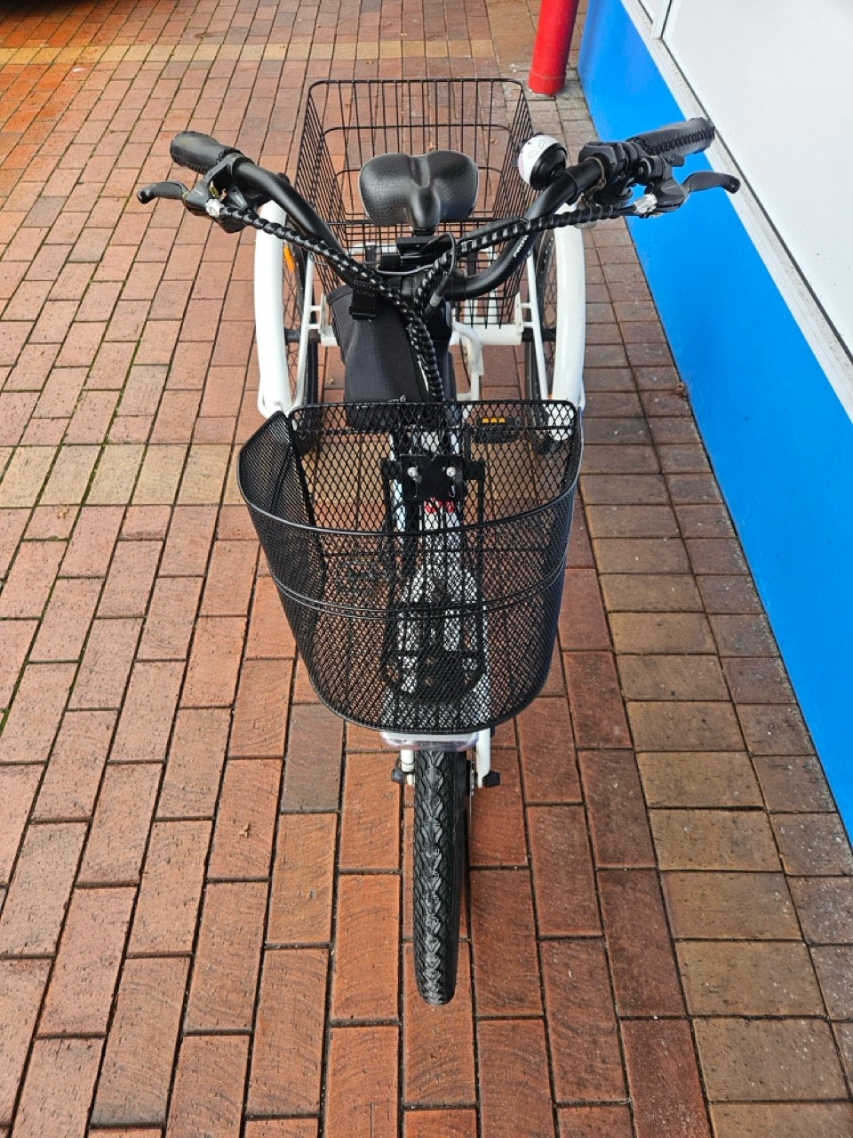 Bicycle with a basket on a brick pavement