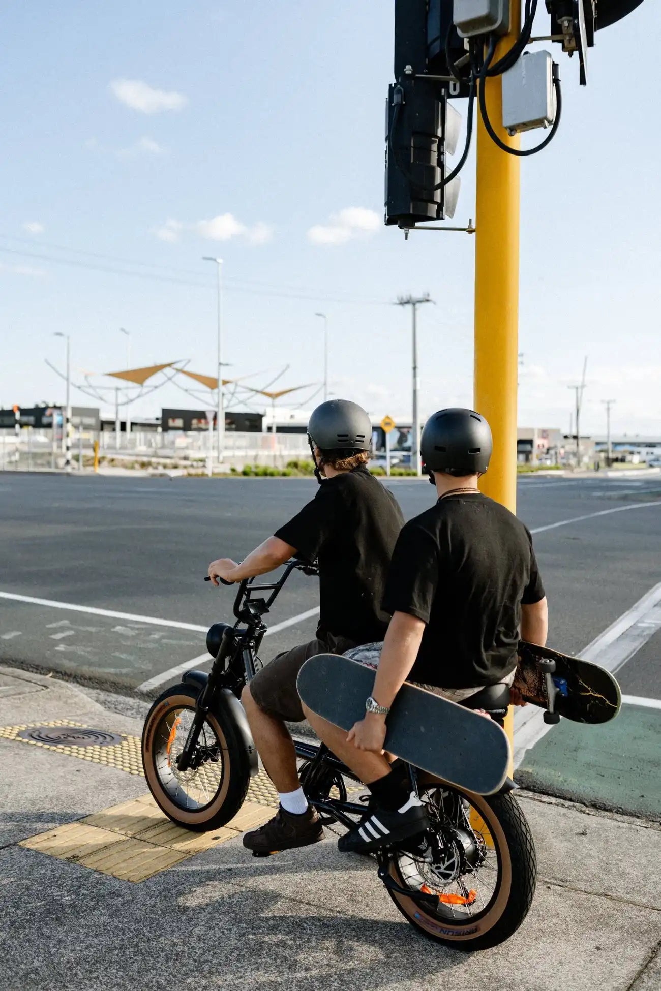 Two people on Smartmotion Renegade E-Bike with skateboards in an urban setting