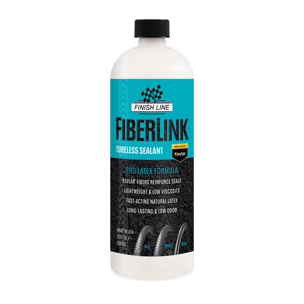 A bottle of Finish Line Fiberlink Pro Latex Tubeless Tyre Sealant in a clear plastic bottle with a black cap. The label includes the product name and features, such as 'Kevlar fibers', 'Pro latex formula', and 'Low odor'.