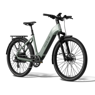 A step-through Aventon electric bicycle in a muted sage green and black colorway, shown from a three-quarters front angle on a clean white background. The brand name 'AVENTON' is clearly visible on the down tube.