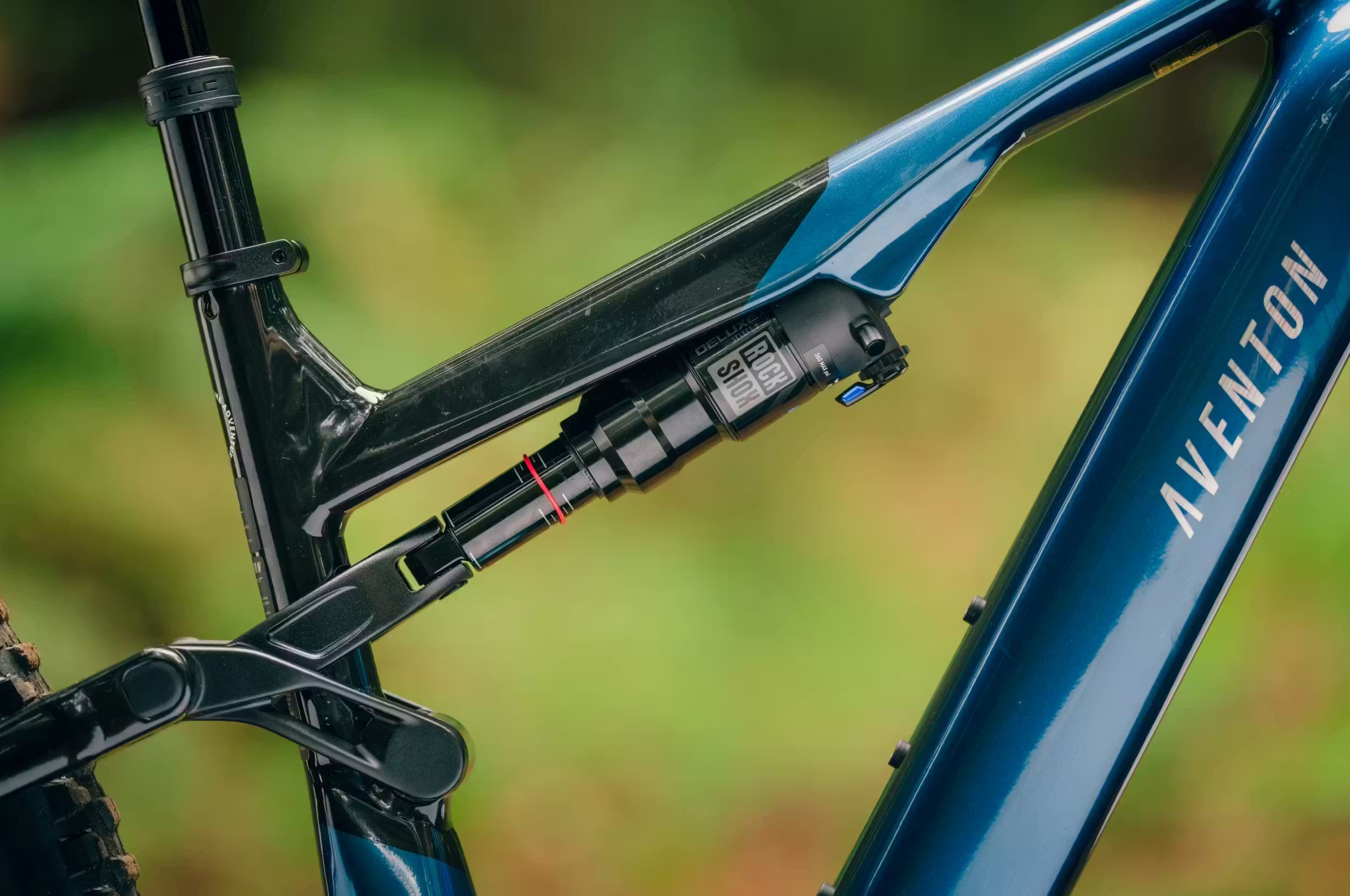 Close-up of a blue Aventon Current Rockshox shock blurred green background