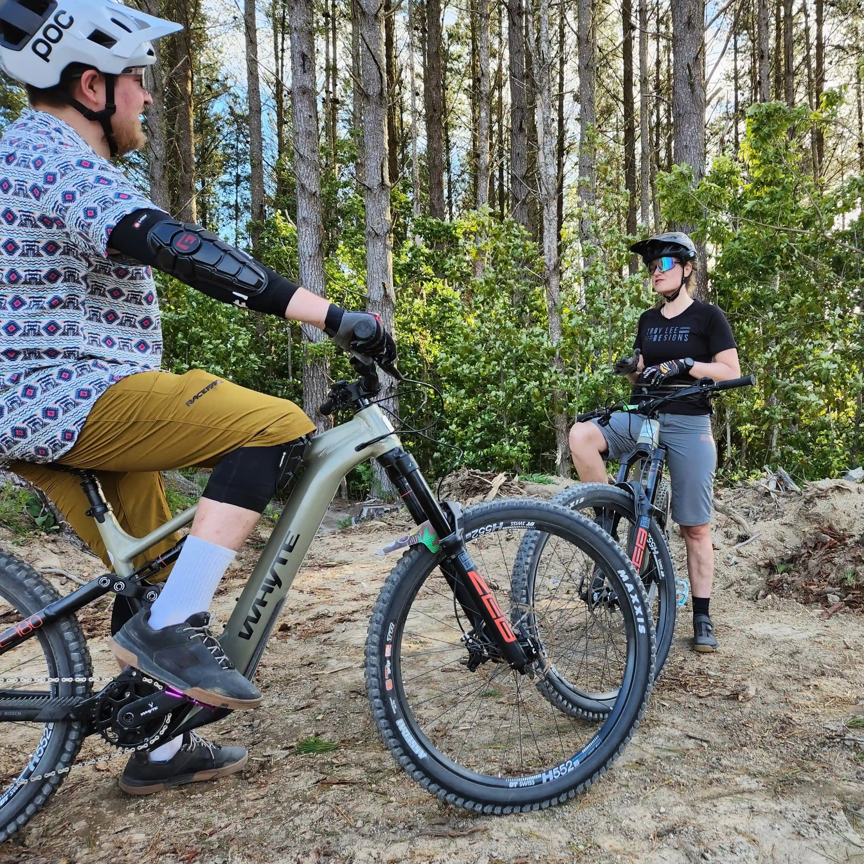 Two people on electric bikes rentals in a the Rotorua Redwoods forest.