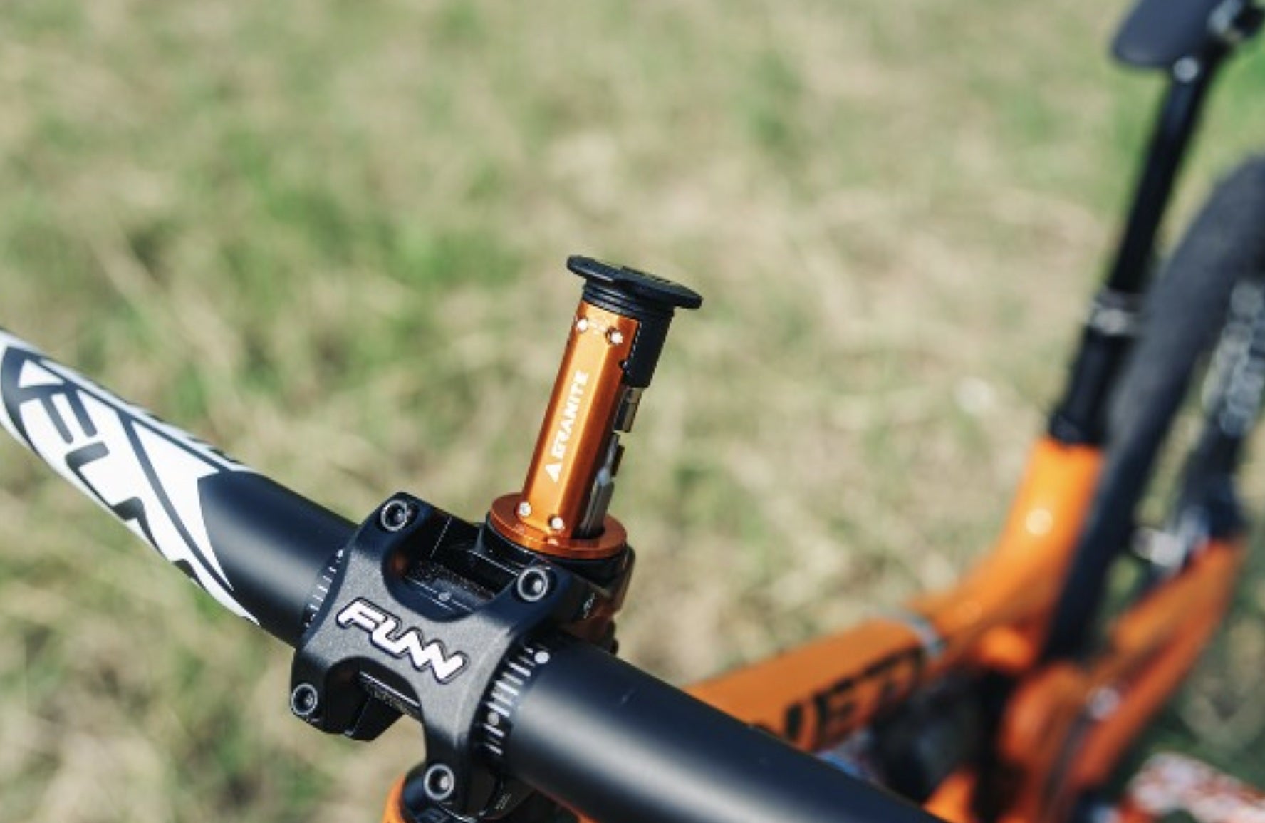 Close-up of a bicycle handlebar with a visible brand logo against a blurred natural background