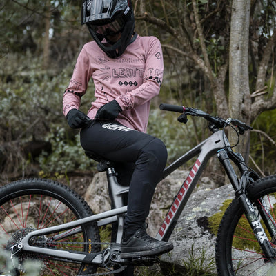 Person on a mountain bike in a forest setting with Leatt MTB Gravity 3.0 Women Pants