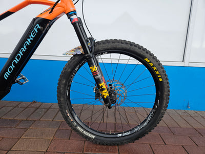 Close-up of a bicycle wheel with visible branding on a tiled floor.