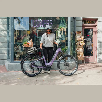 Person with a purple Aventon Trava ADV electric bike in front of a store with a 'Flowers' sign.