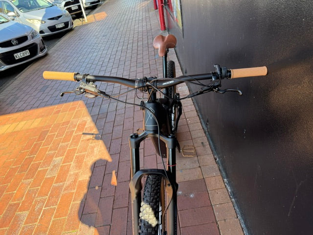 Rhyolite Base+ leaning against a wall on a sidewalk with cars in the background