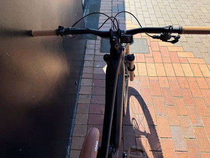 Rhyolite E-bike handlebars and front wheel on a brick sidewalk