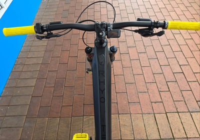 Rhyolite eMTB handlebar with yellow grips on a brick pavement