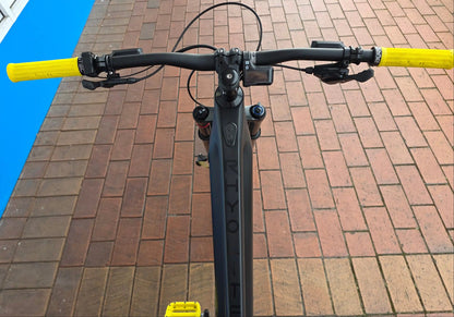 Rhyolite eMTB handlebar with yellow grips on a brick pavement