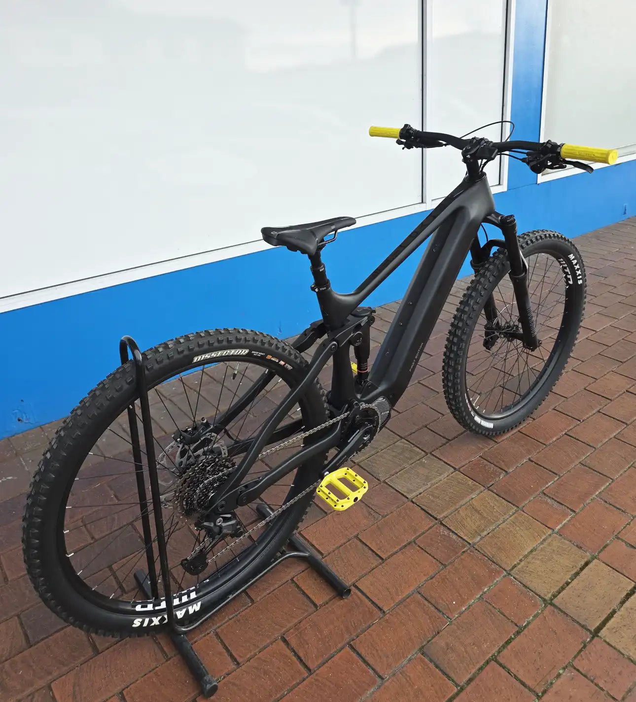 Black Rhyolite E-MTB on a stand against a blue and white wall.