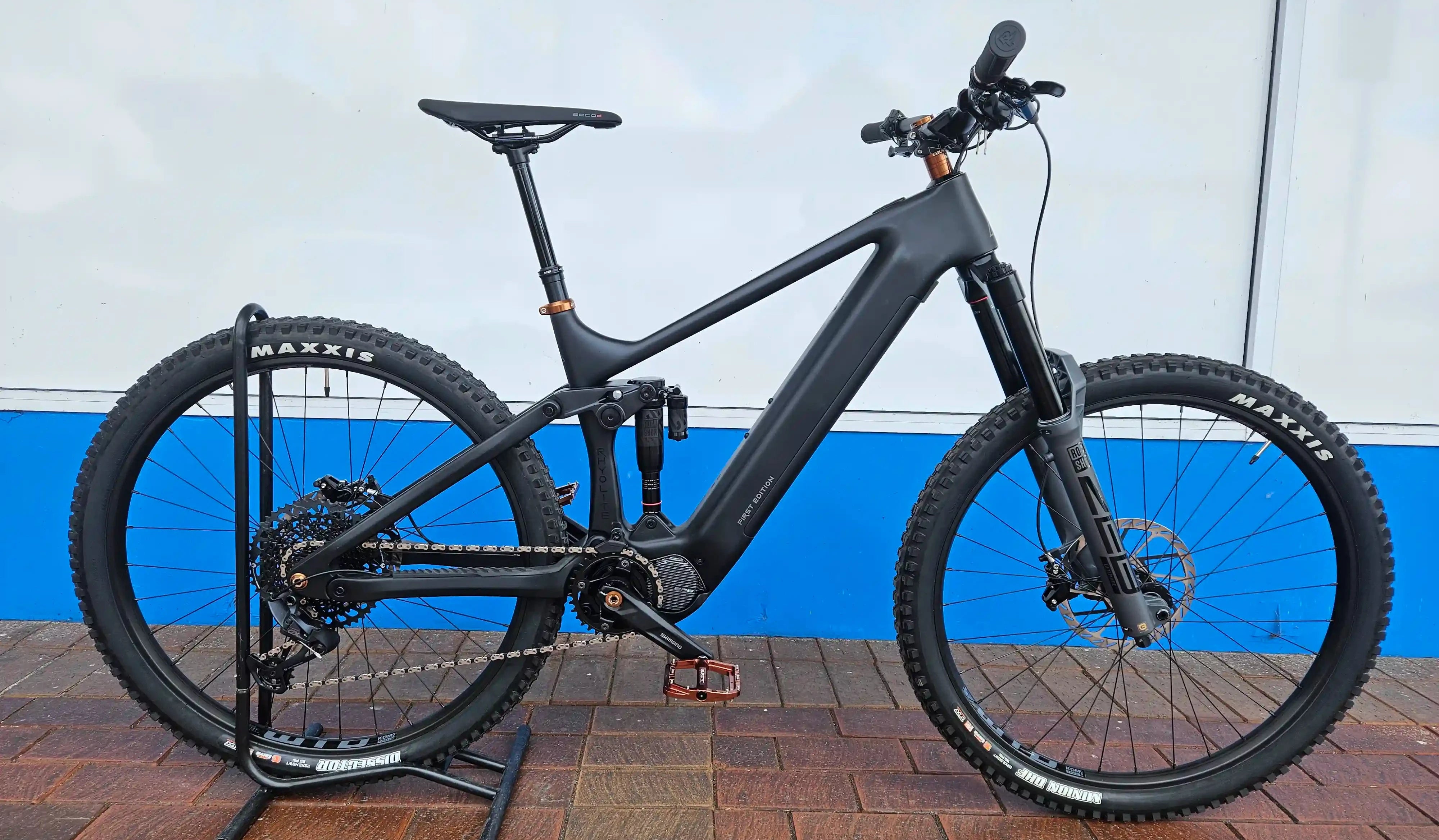 Rhyolite Prime E-MTB on a stand against a white and blue wall.