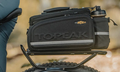 Black Topeak bike bag attached to a bicycle with a blurred natural background