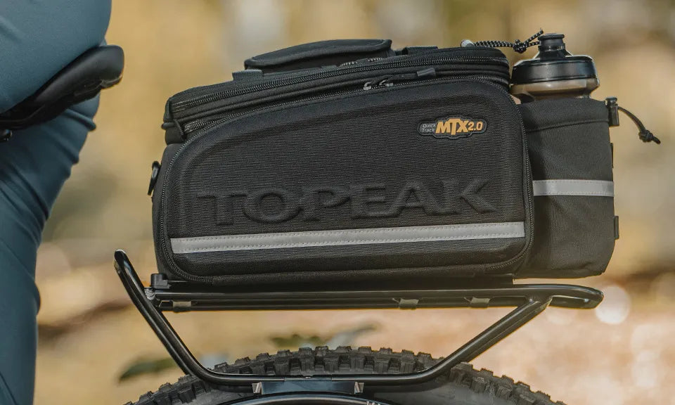Black Topeak bike bag attached to a bicycle with a blurred natural background