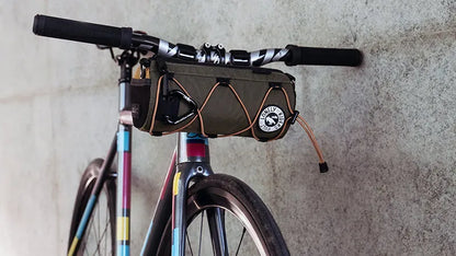 Bicycle with a handlebar bag, ULAC Neo Porter Coursier, against a concrete wall