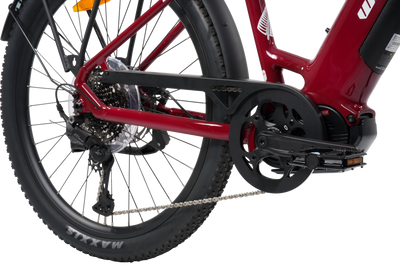 Close-up of a red electric bicycle showing the rear wheel, chain guard, chain, crankset, and part of the frame against a white background.