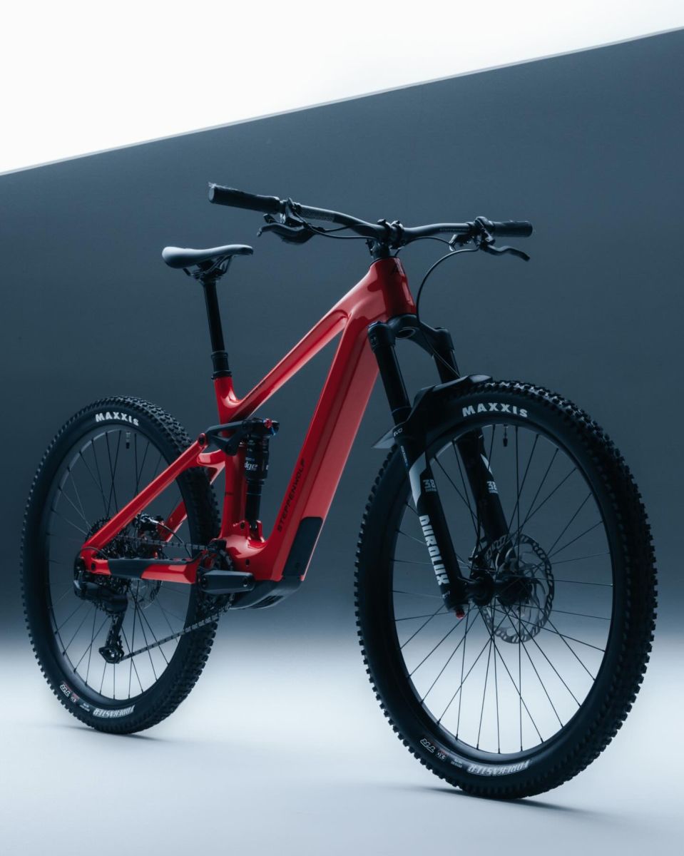 A red and black Steppenwolf Tundra 9 full-suspension electric mountain bike with Maxxis tires, displayed on a clean, two-tone gray studio background.
